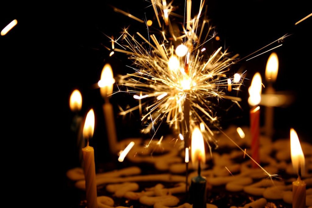 a birthday cake with sparkler and standard candles